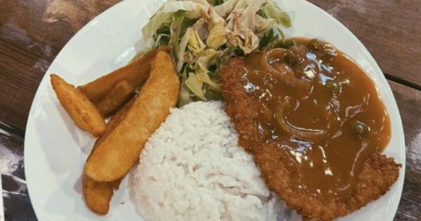 Hainanese pork chop served with rice and fries in brown sauce