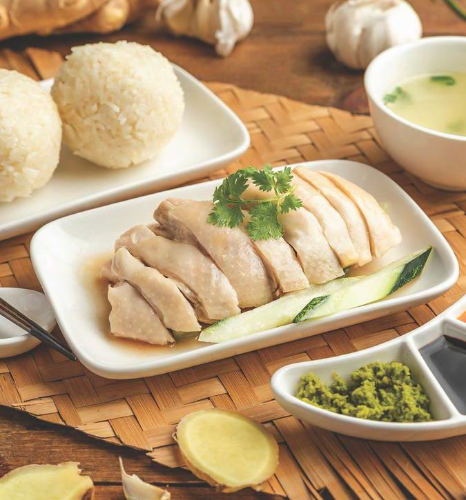 Hainanese chicken rice served with traditional rice balls and ginger