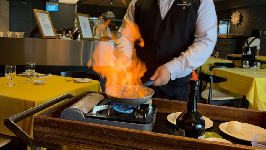 Flames rising from a flambéed dish prepared at a Shashlik table