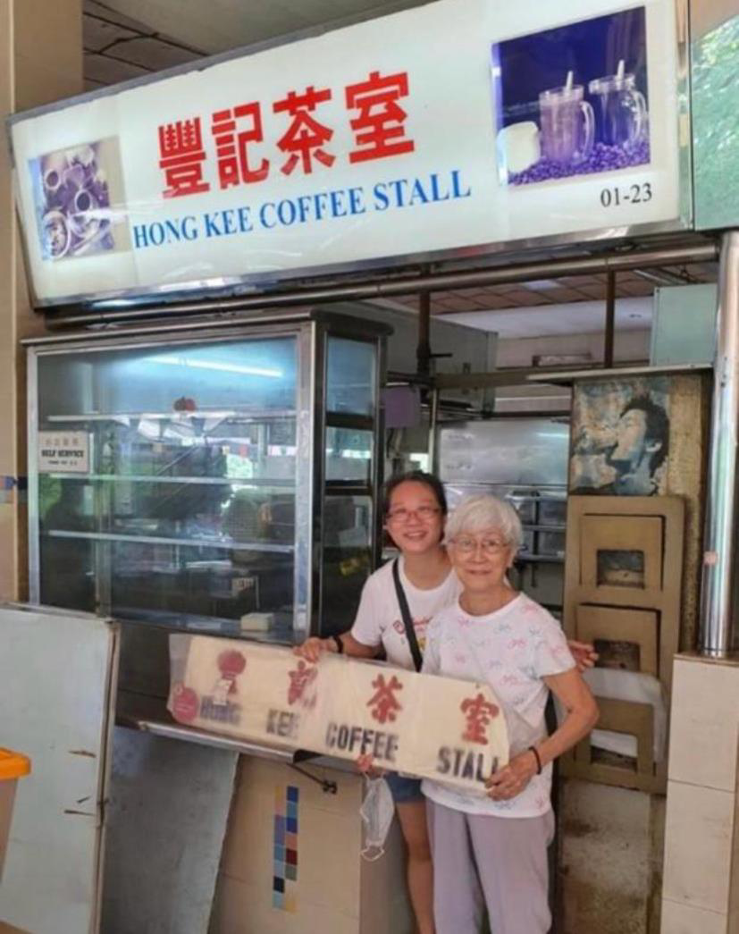 Kim and her mother at the Hong Kee Coffee Stall holding the old signboard